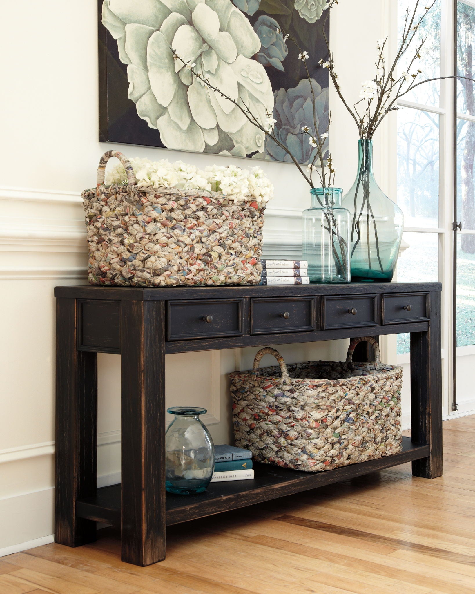 Black sofa table with drawers and open shelf, display items underneath