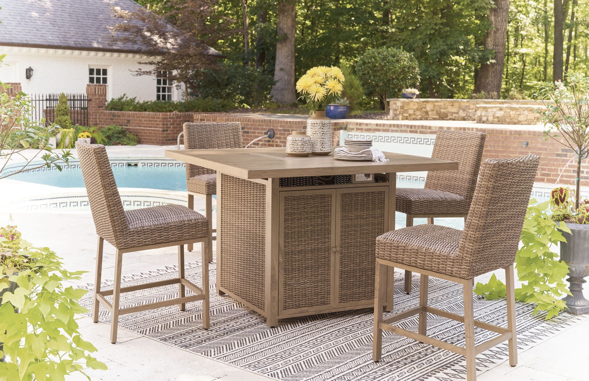 Outdoor patio bar table with fire pit and four matching rattan bar stools