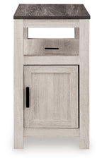 Chair side end table with open shelf and single door cabinet, light wood finish, black pulls.