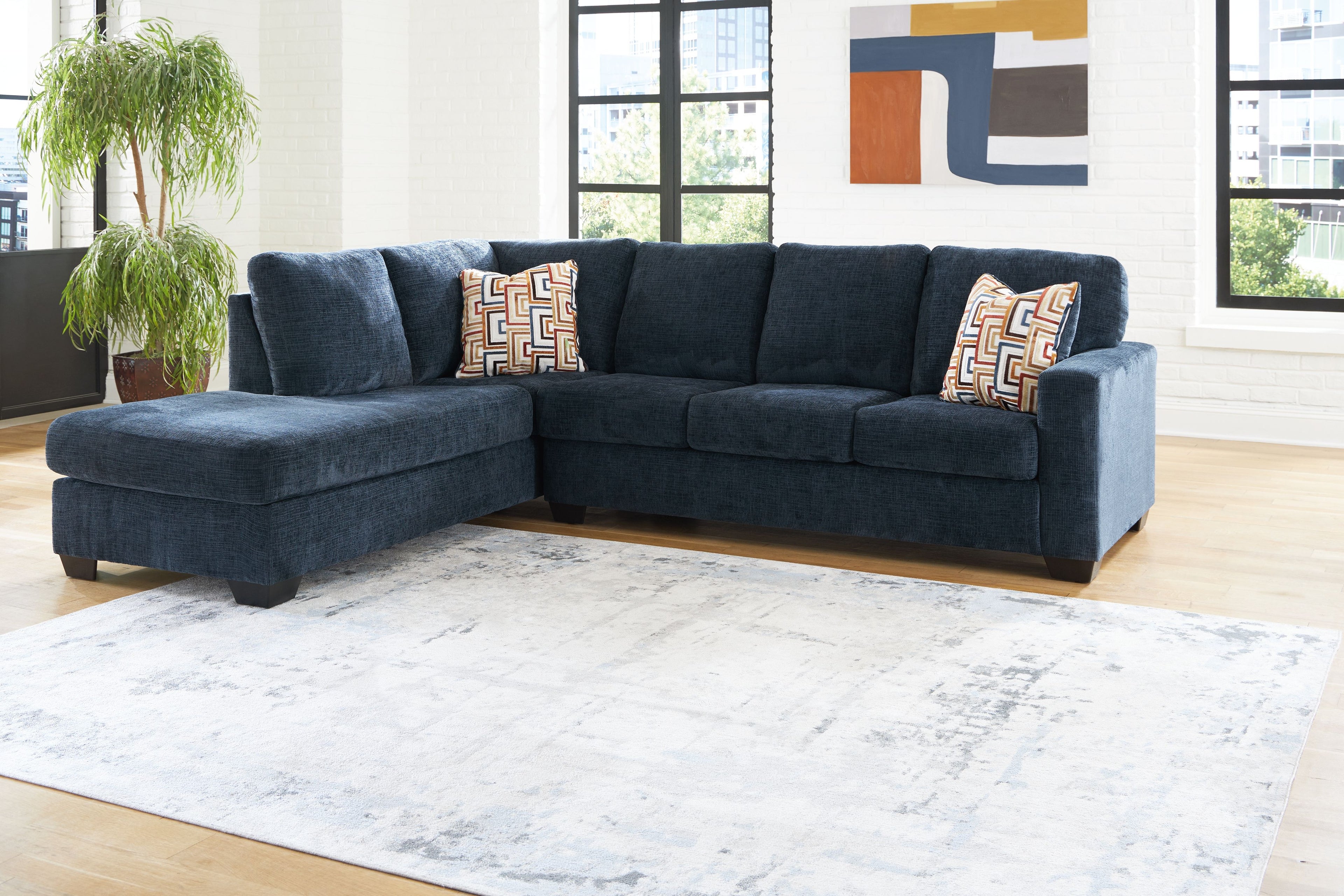 Dark navy sectional sofa with corner chaise and patterned accent pillows