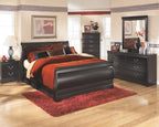 Black sleigh bed with red-orange comforter and patterned throw pillows