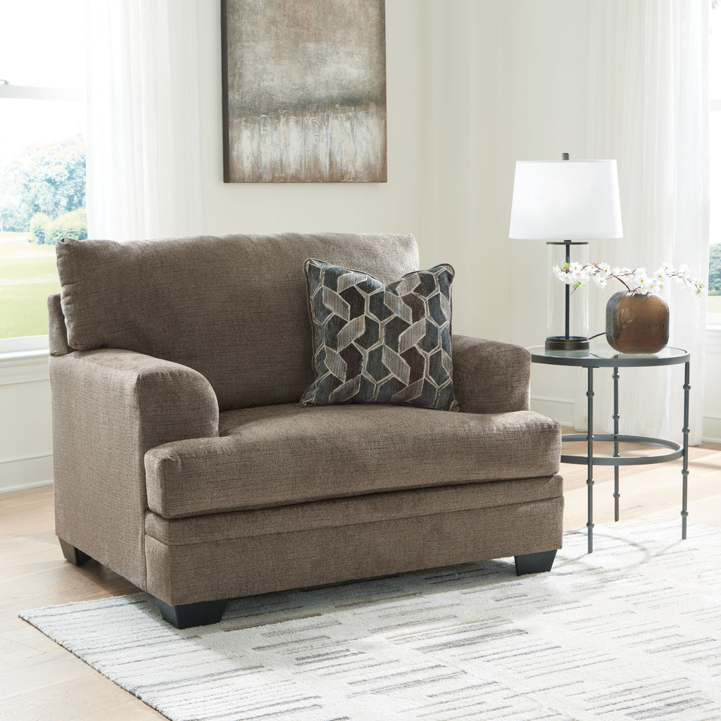 Medium beige chair-and-a-half armchair with geometric patterned throw pillow