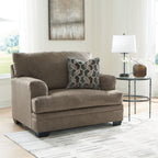 Medium beige chair-and-a-half armchair with geometric patterned throw pillow
