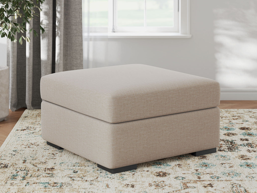 Light beige upholstered ottoman with cushioned top and black block legs