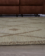Beige rug close-up with brown swoosh lines and X/diamond geometric pattern.