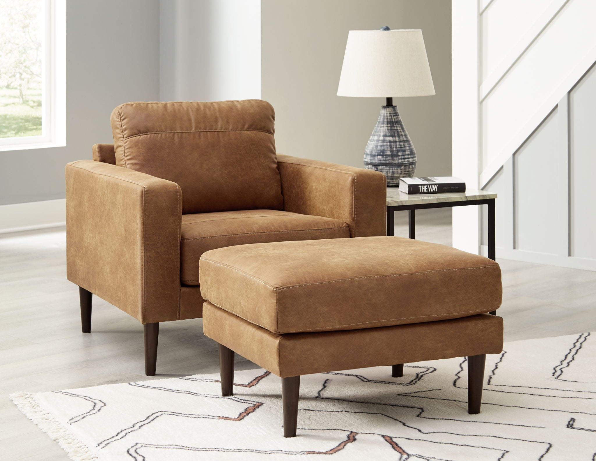 Light brown upholstered armchair with matching ottoman and rounded arms