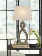 Table lamp with off-white drum shade and gray hourglass-style cutout base