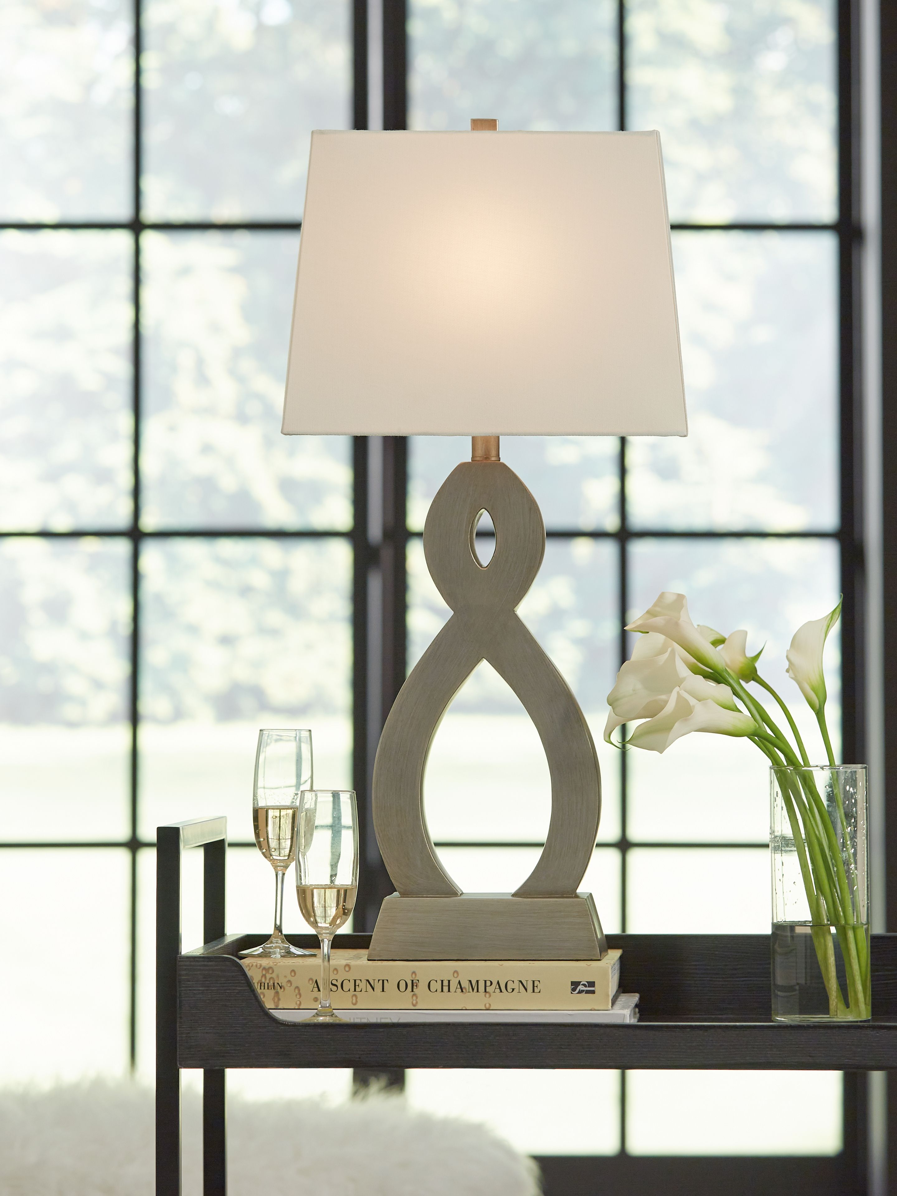 Table lamp with off-white drum shade and gray hourglass-style cutout base