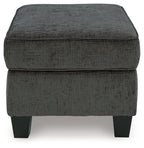 Dark gray ottoman with buttonless cushioned sides and flat square top, block legs
