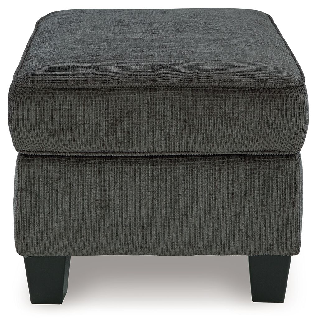 Dark gray ottoman with buttonless cushioned sides and flat square top, block legs