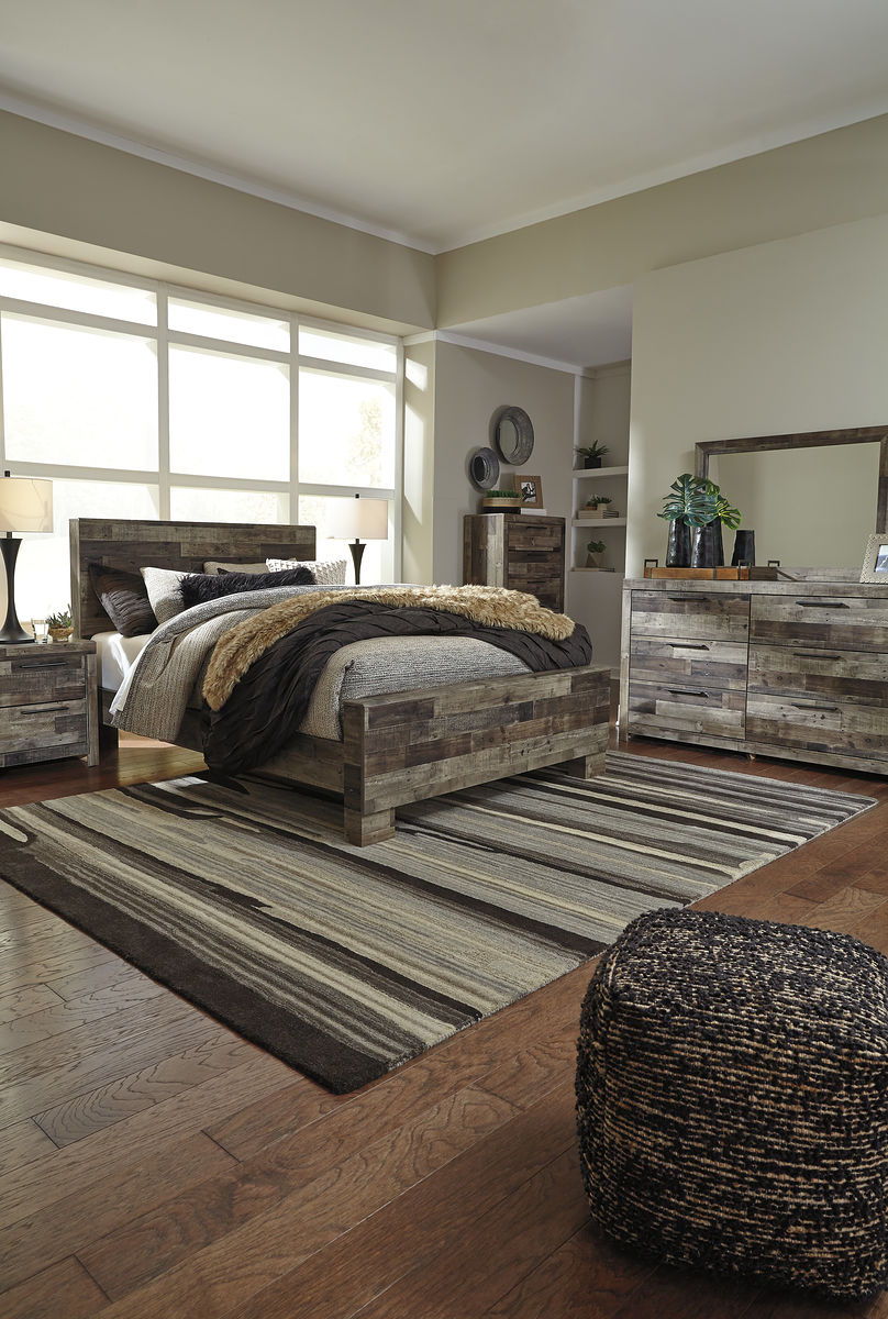 Dark wood panel bed frame with tan faux-fur throw and gray bedding on striped rug