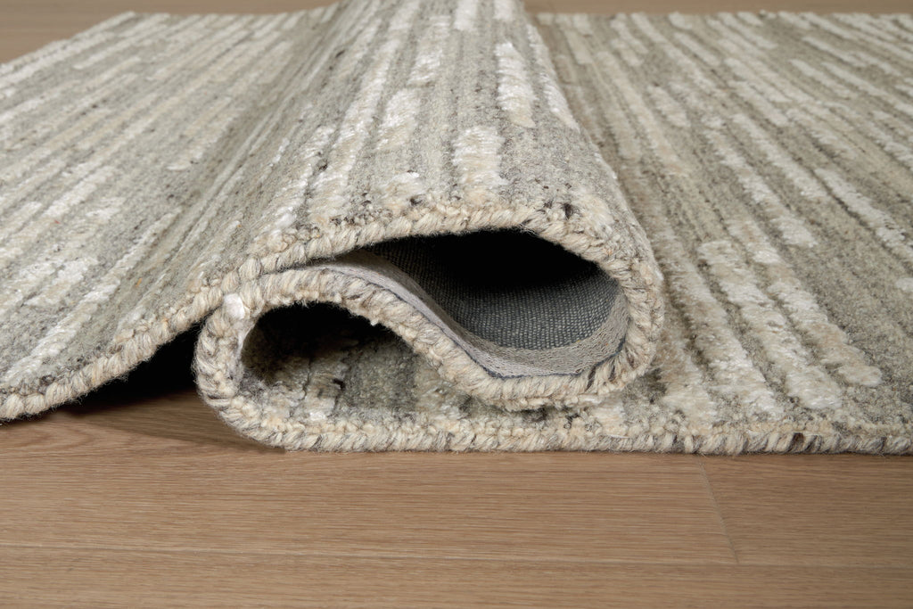 Gray rug with visible edge stitching and low pile rolled section