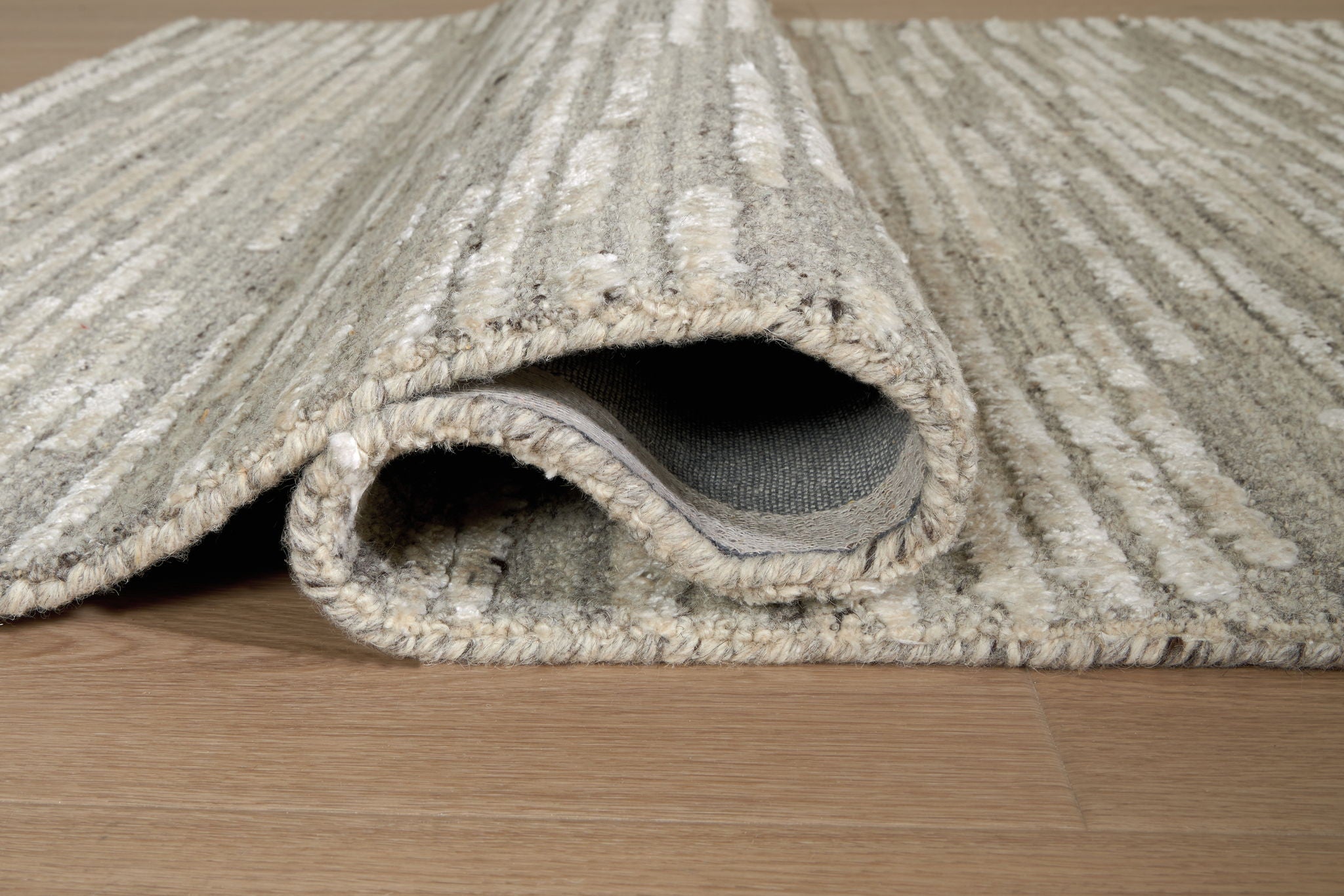 Gray rug with visible edge stitching and low pile rolled section