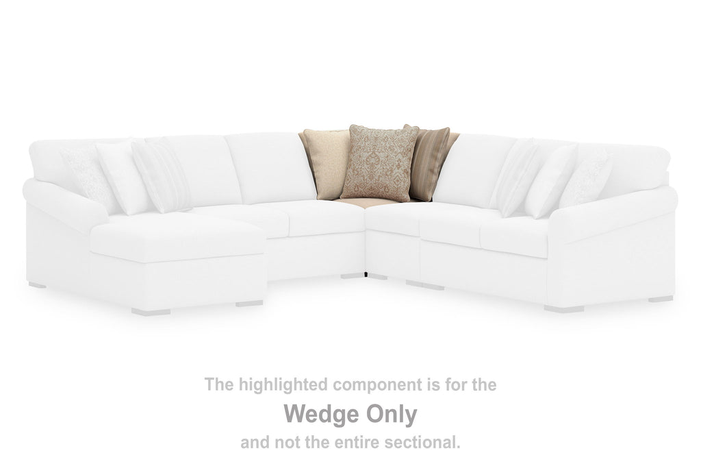 White wedge sectional with curved chaise corner and two neutral throw pillows