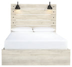 Light wood panel bed with two front drawers; white bedding and two black lamps on headboard