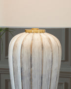Striped poly table lamp base with brass-toned top cap and white drum shade