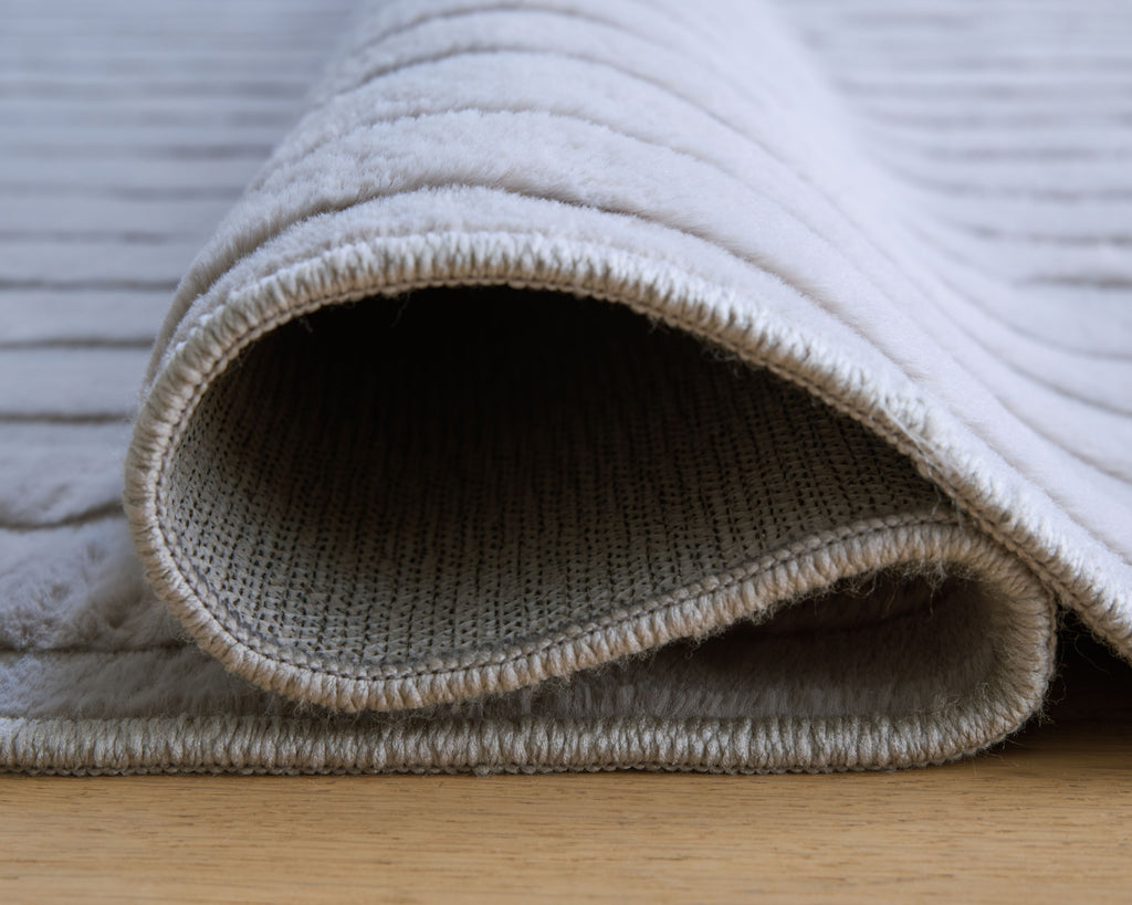 Gray washable rug edge with curled border and textured woven pile