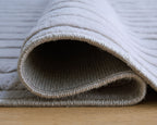 Gray washable rug edge with curled border and textured woven pile