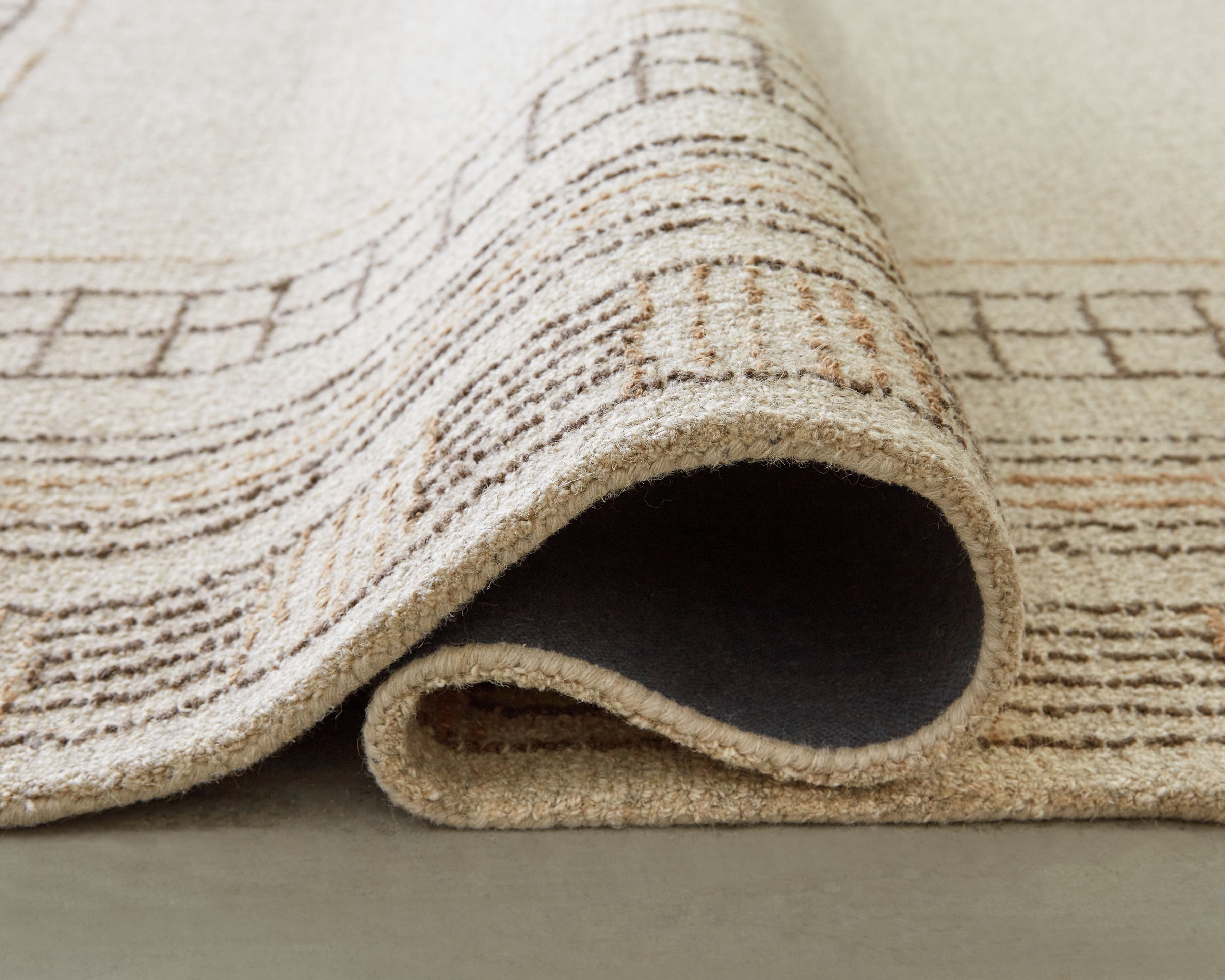Beige rug corner with rolled underside and stitched geometric details
