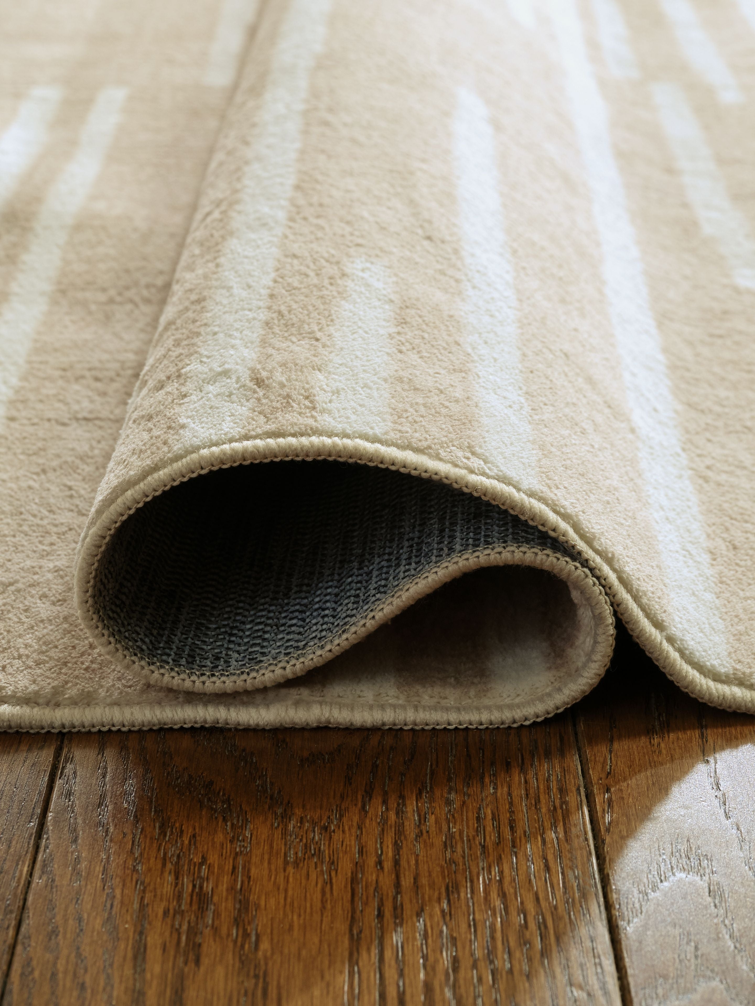 Beige area rug edge with bound border and textured underside