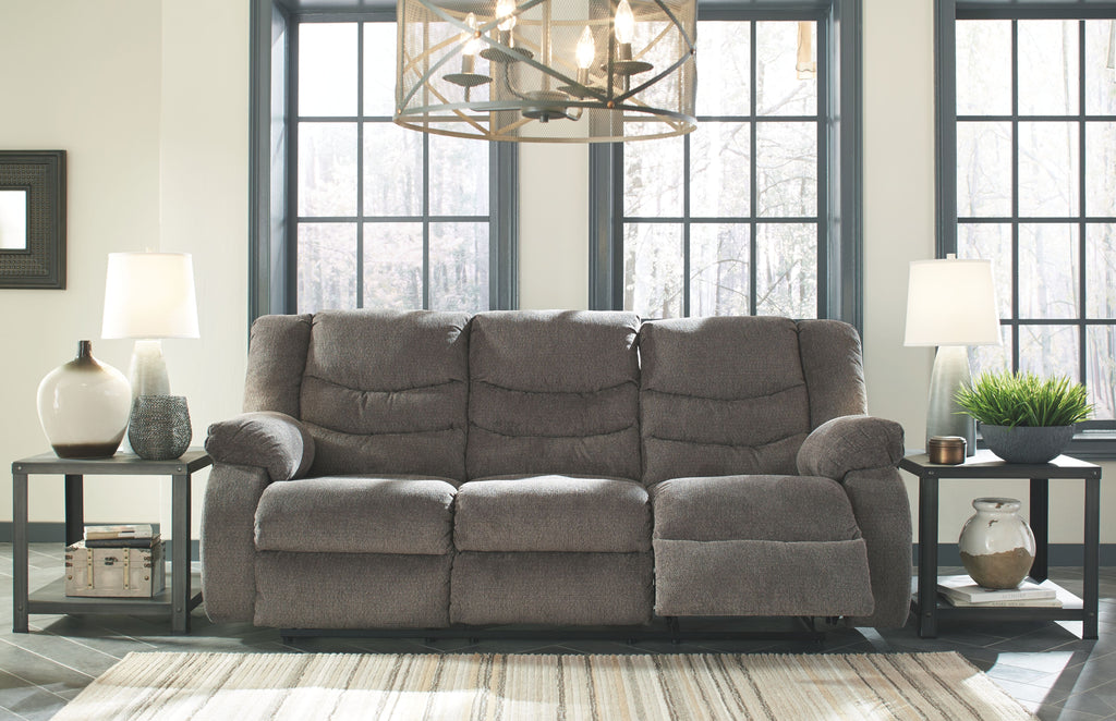 Gray reclining sofa with extended footrest and padded headrest cushions