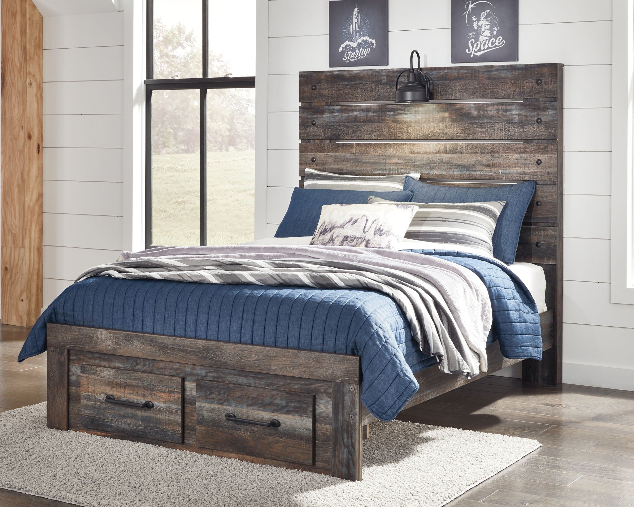 Panel bed with two side drawers in dark distressed wood, layered bedding with blue throw