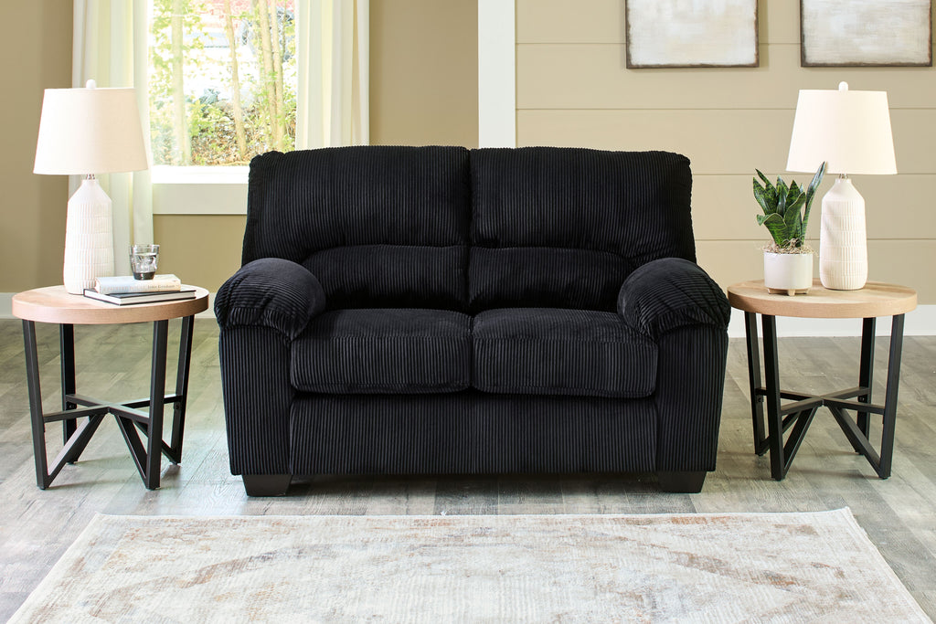 Black corduroy loveseat with rolled arms, two-seat cushions, and dark base feet