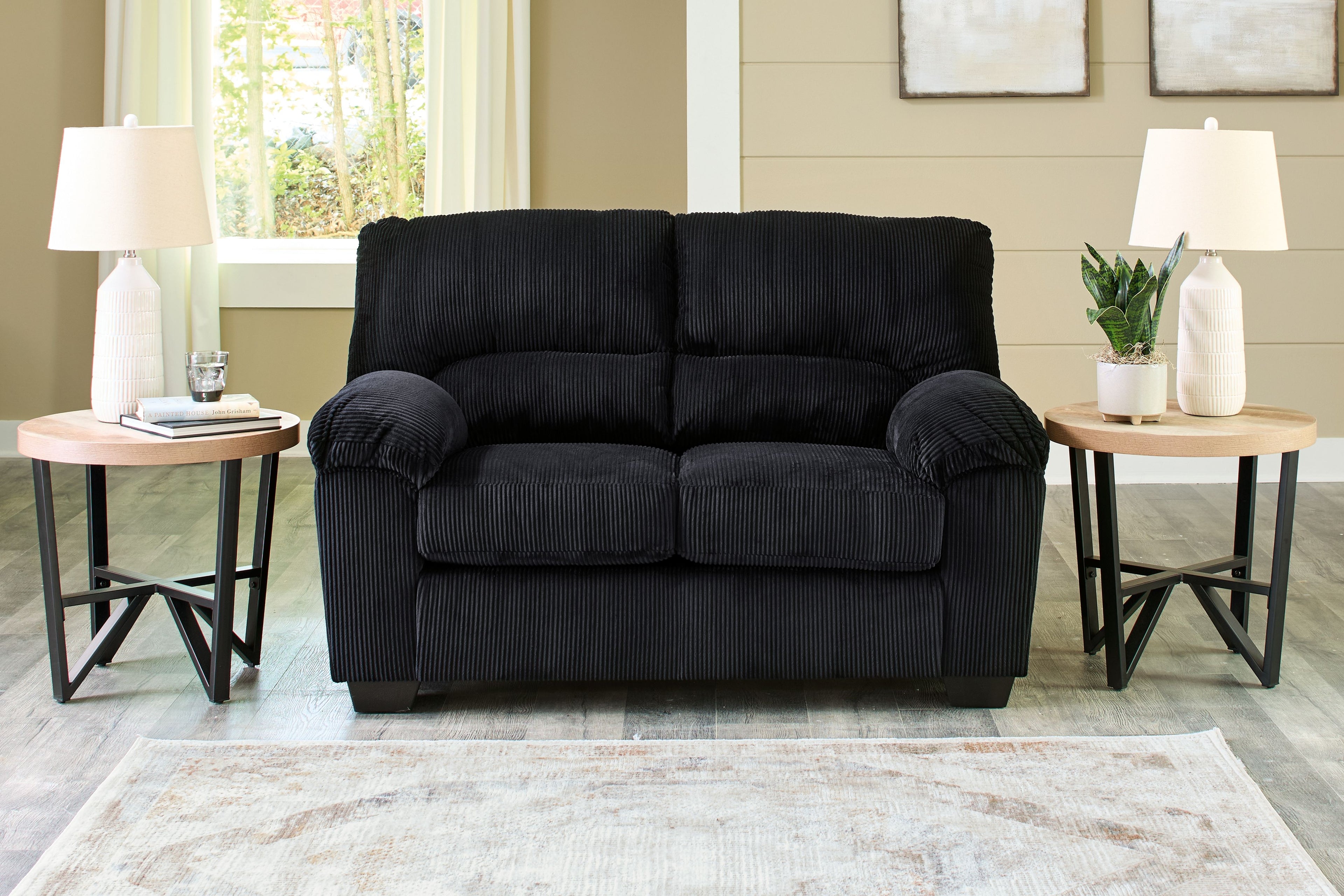 Black corduroy loveseat with rolled arms, two-seat cushions, and dark base feet