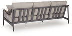 Gray outdoor sofa with back slats, seat cushions, and two geometric throw pillows, dark legs