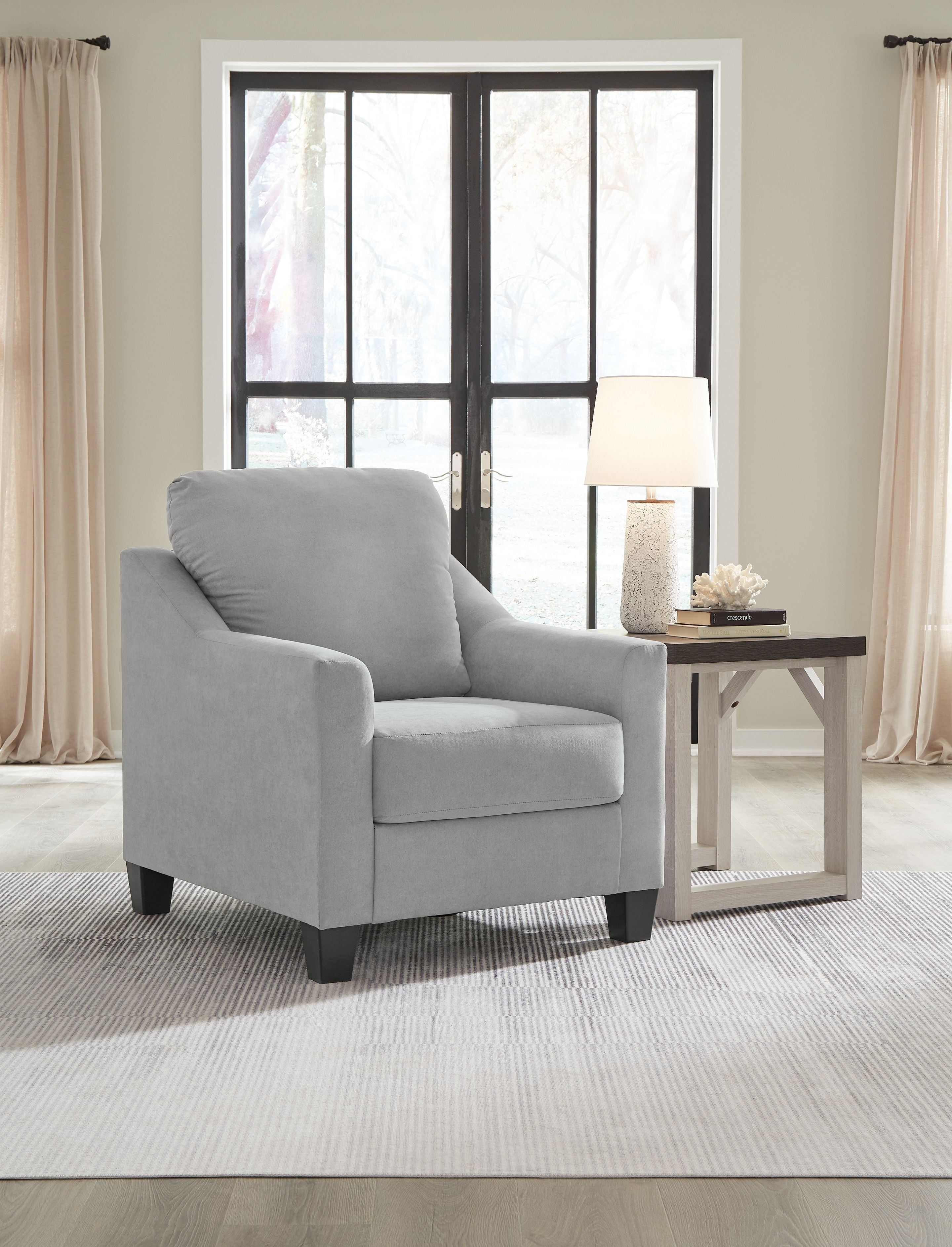 Light gray upholstered accent chair with tall back and padded arms, dark legs visible.