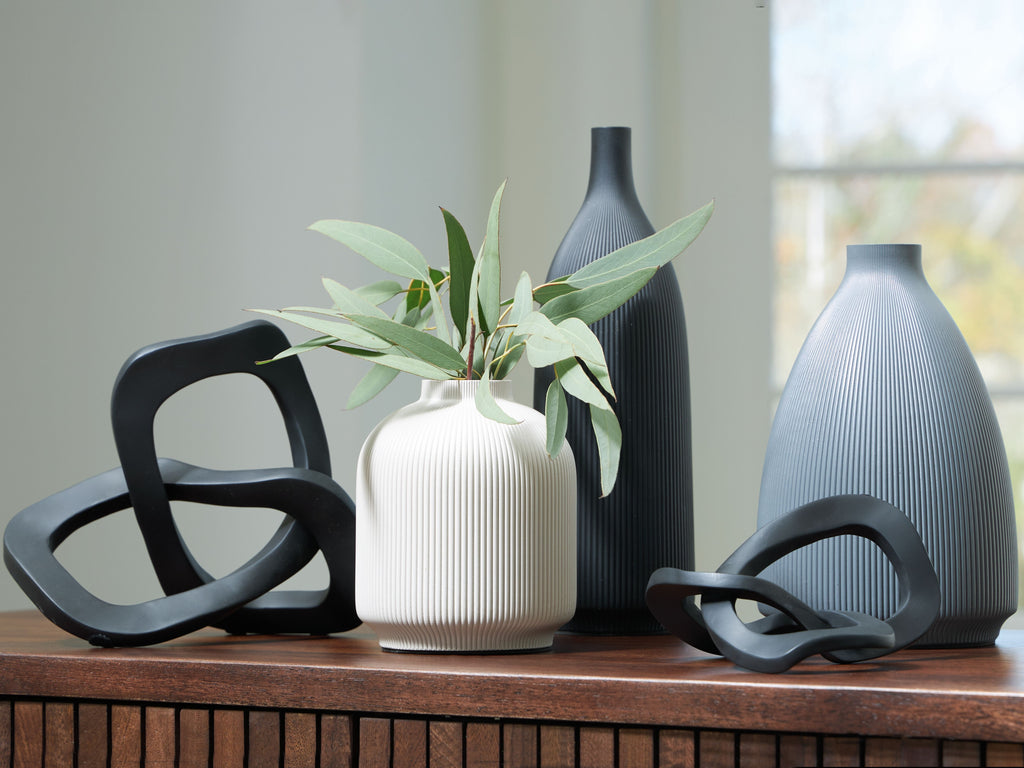 Ribbed ceramic vases with black loop accents, including a white vase with stems