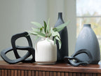 Ribbed ceramic vases with black loop accents, including a white vase with stems
