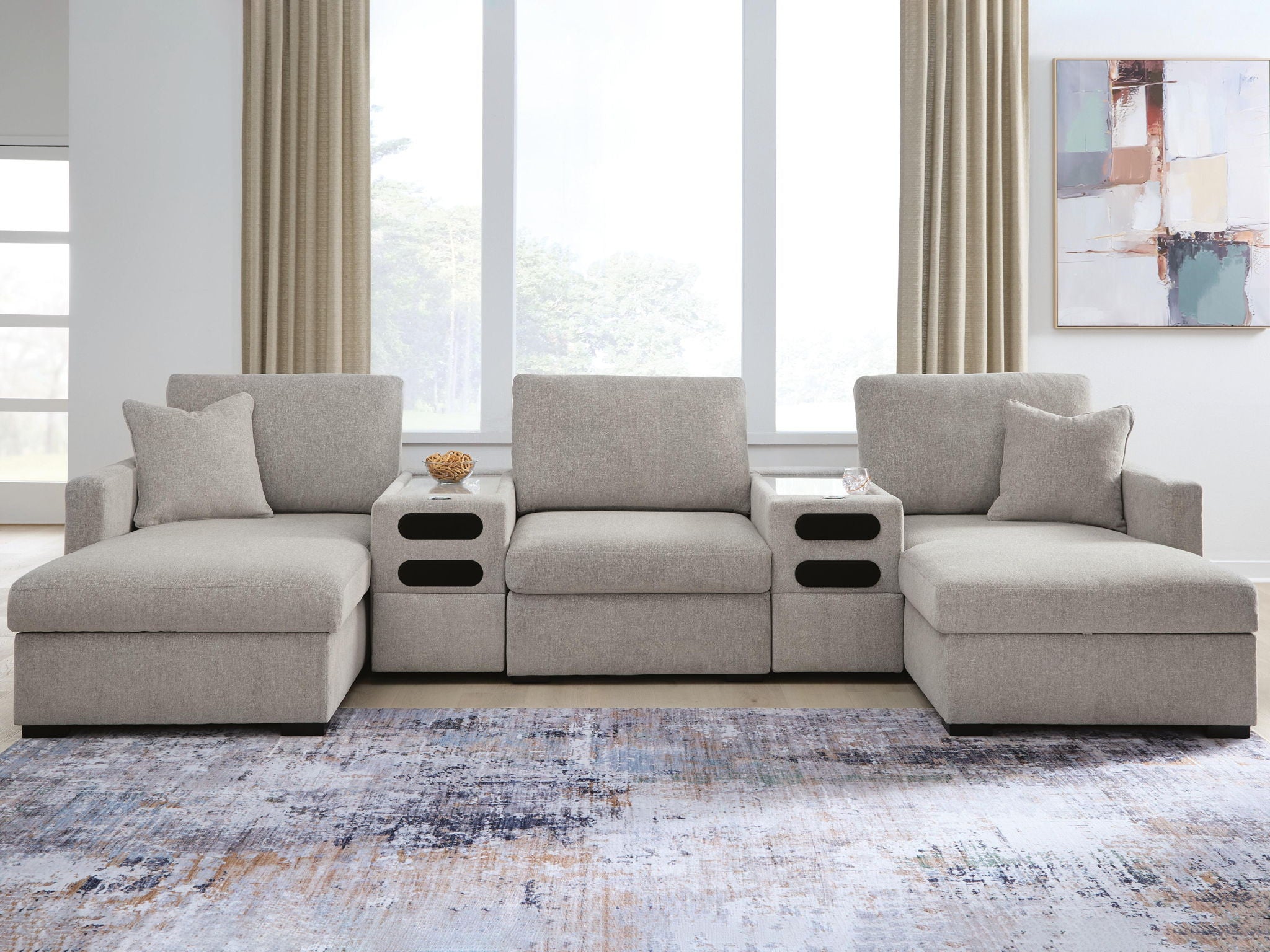 Gray sectional sofa with chaise seating and dark audio console panels at both side ends