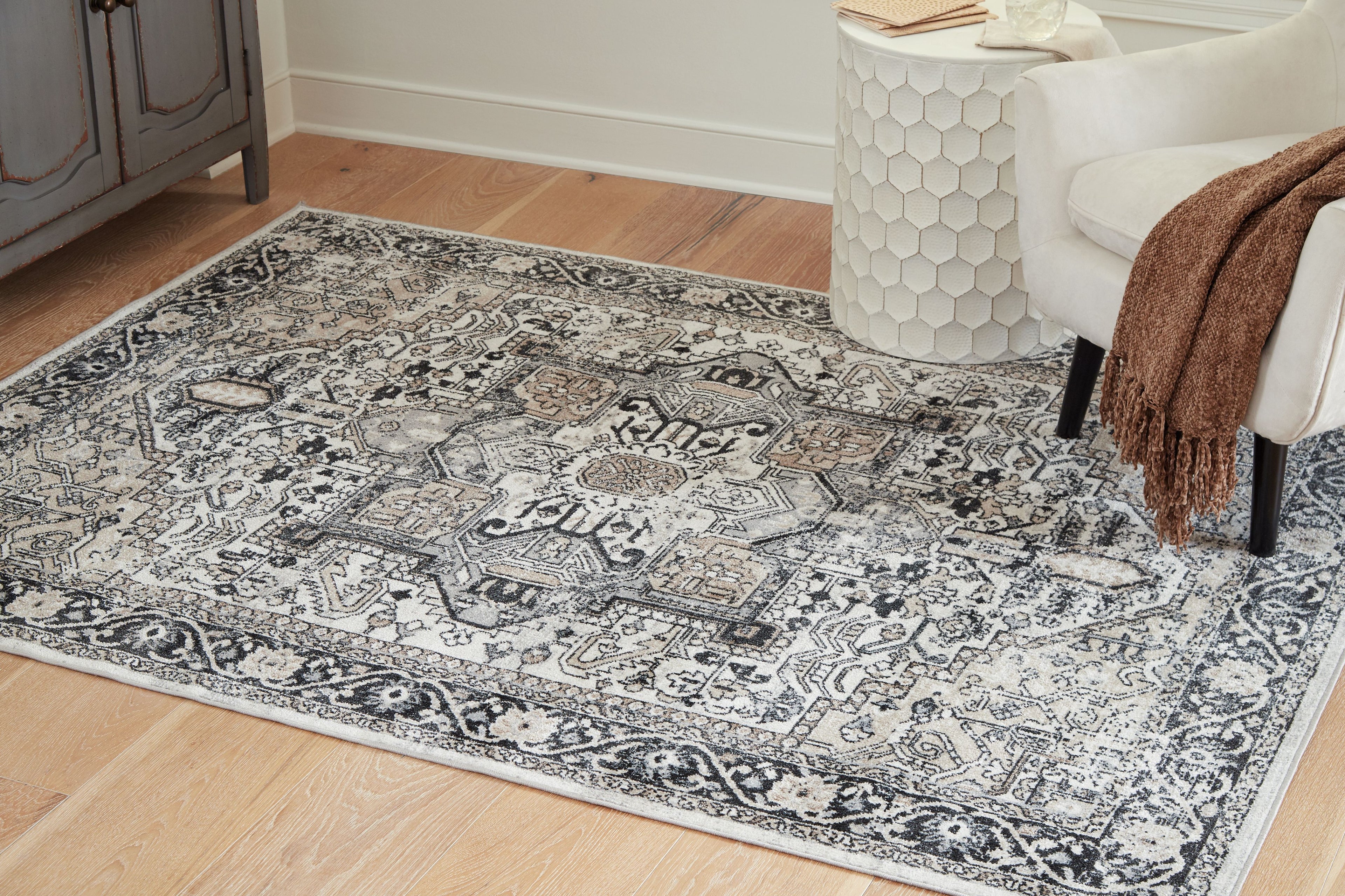 Light gray area rug with dark geometric motifs and central medallion, wide border