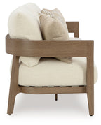 Outdoor lounge loveseat side view with beige cushions and patterned throw pillow