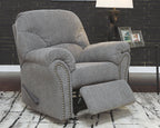 Dark gray recliner chair with padded armrests, tufted back, and studded trim