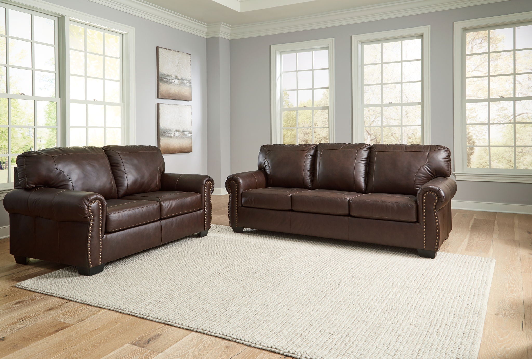 Dark brown upholstered sofa and loveseat set with rolled arms and nailhead trim