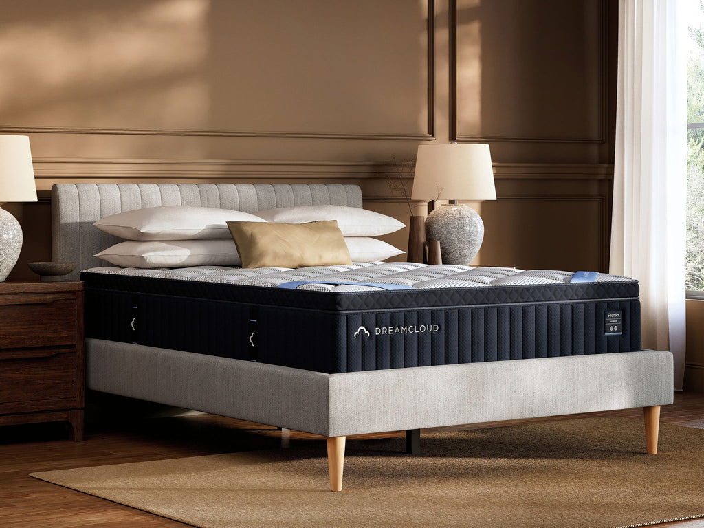 DreamCloud Premier hybrid mattress with white quilted top and dark blue base on bed frame