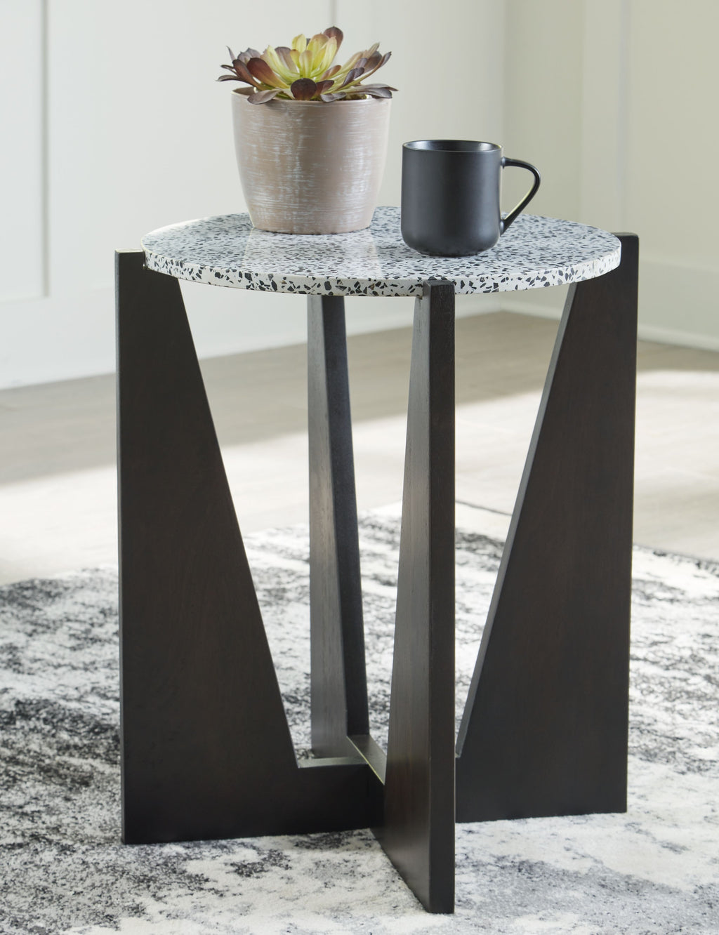Round accent table with speckled white top and tall dark open-frame legs