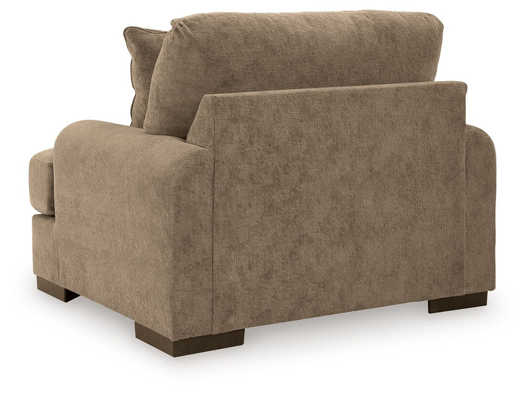 Armchair in light brown fabric with wide arms and dark wooden legs, viewed from side angle