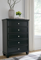 Dark five-drawer chest with round knobs and stacked drawer fronts