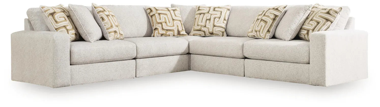 Light beige corner sectional sofa with chaise ottoman ends and patterned throw pillows.