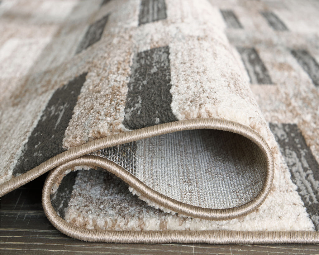 Beige abstract area rug with rounded border and dark gray block motif