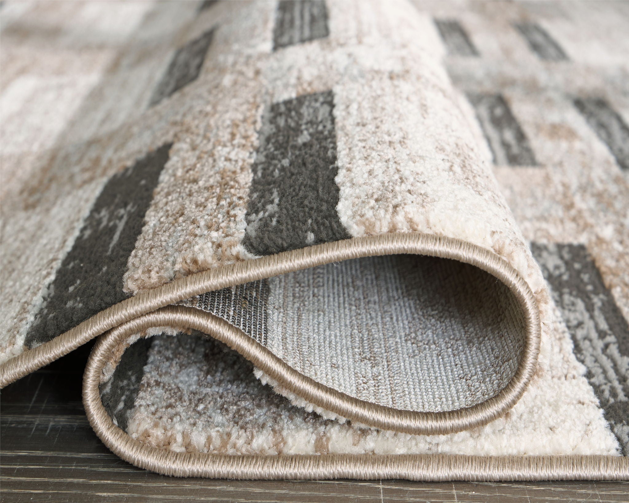 Beige abstract area rug with rounded border and dark gray block motif