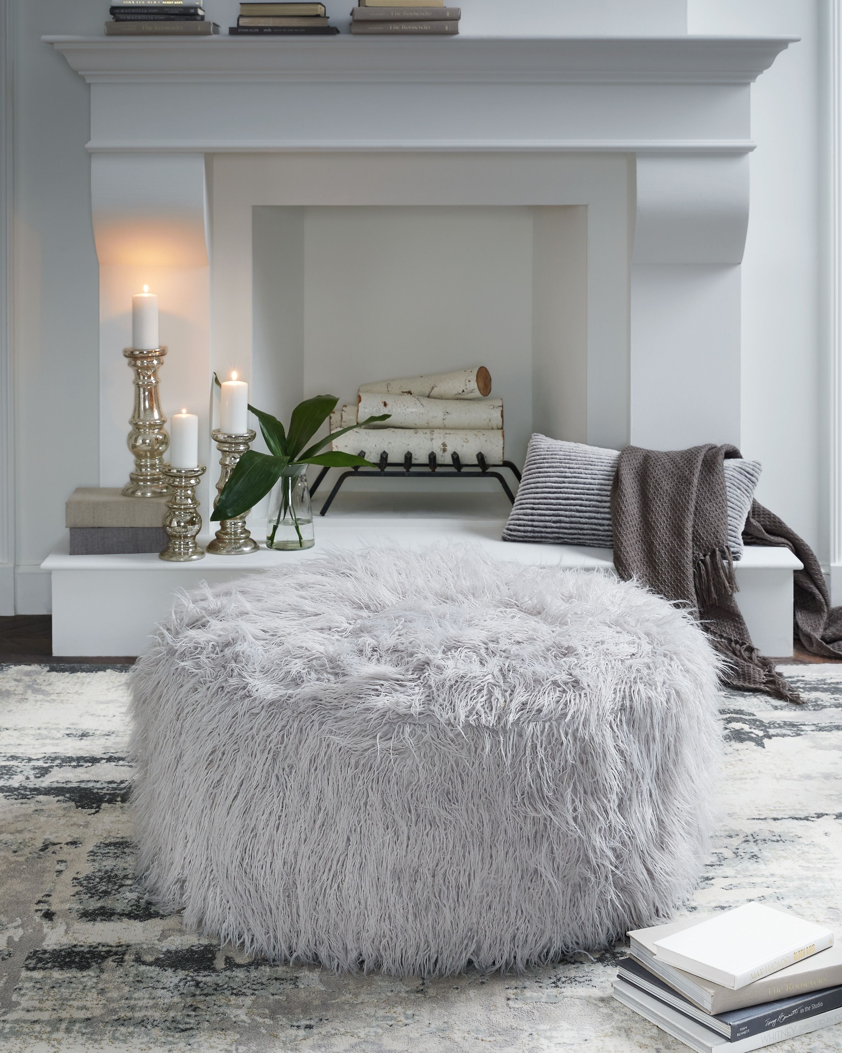 Oversized ottoman with shaggy light gray faux fur upholstery and rounded silhouette
