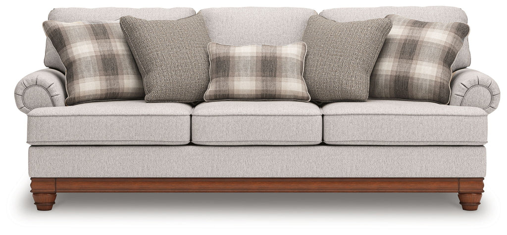 Light gray sofa with plaid pillows, tufted arms, and wooden legs