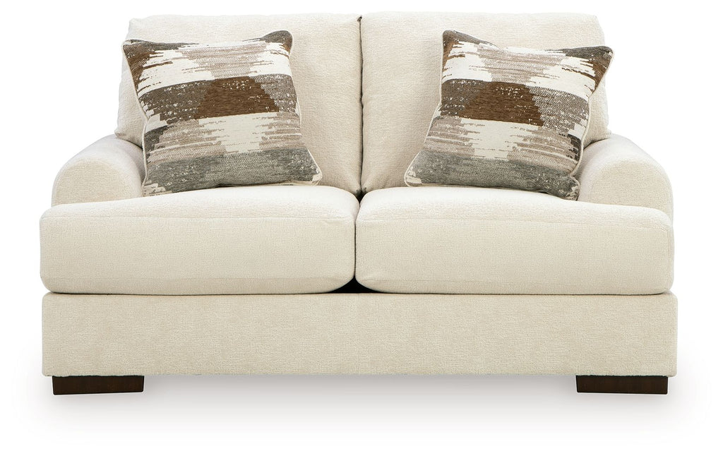 Cream loveseat sofa with two seat cushions and two patterned accent pillows, square arms