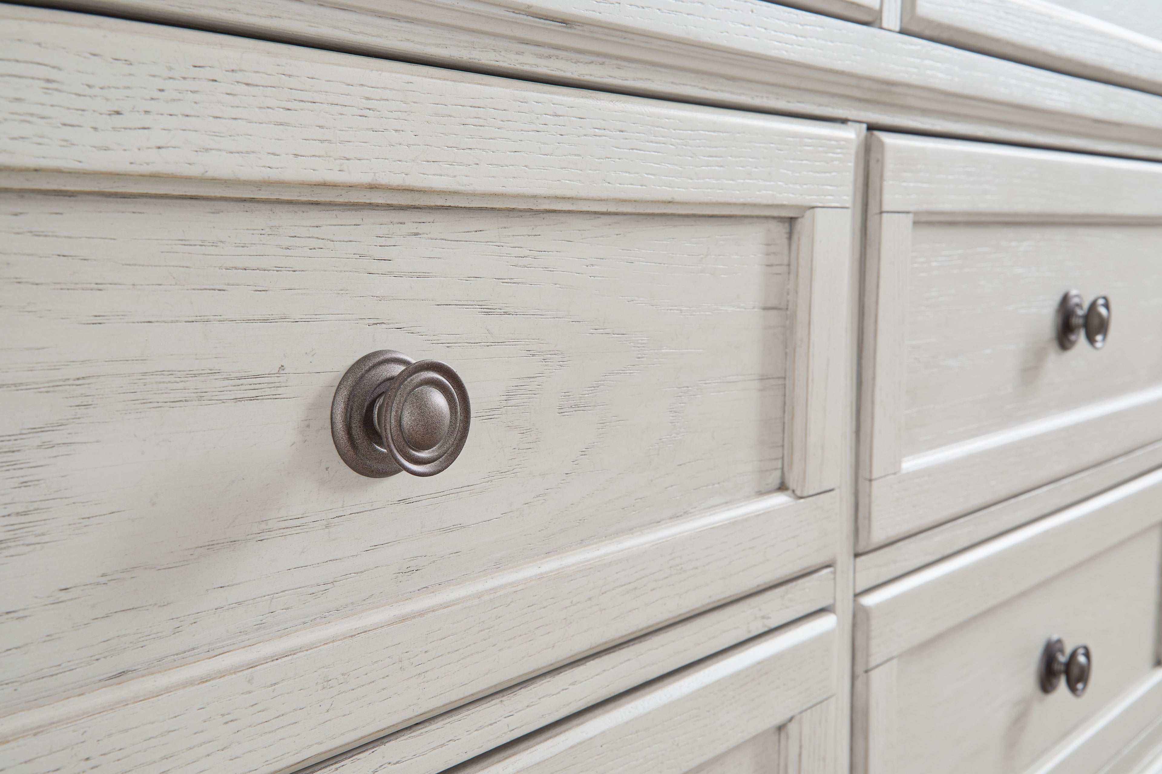 Antique white dresser drawer fronts with round metal knobs, distressed wood grain