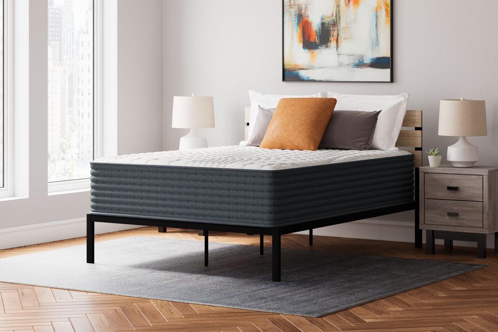 Hybrid mattress with white quilted top and dark gray sides, on a bed frame