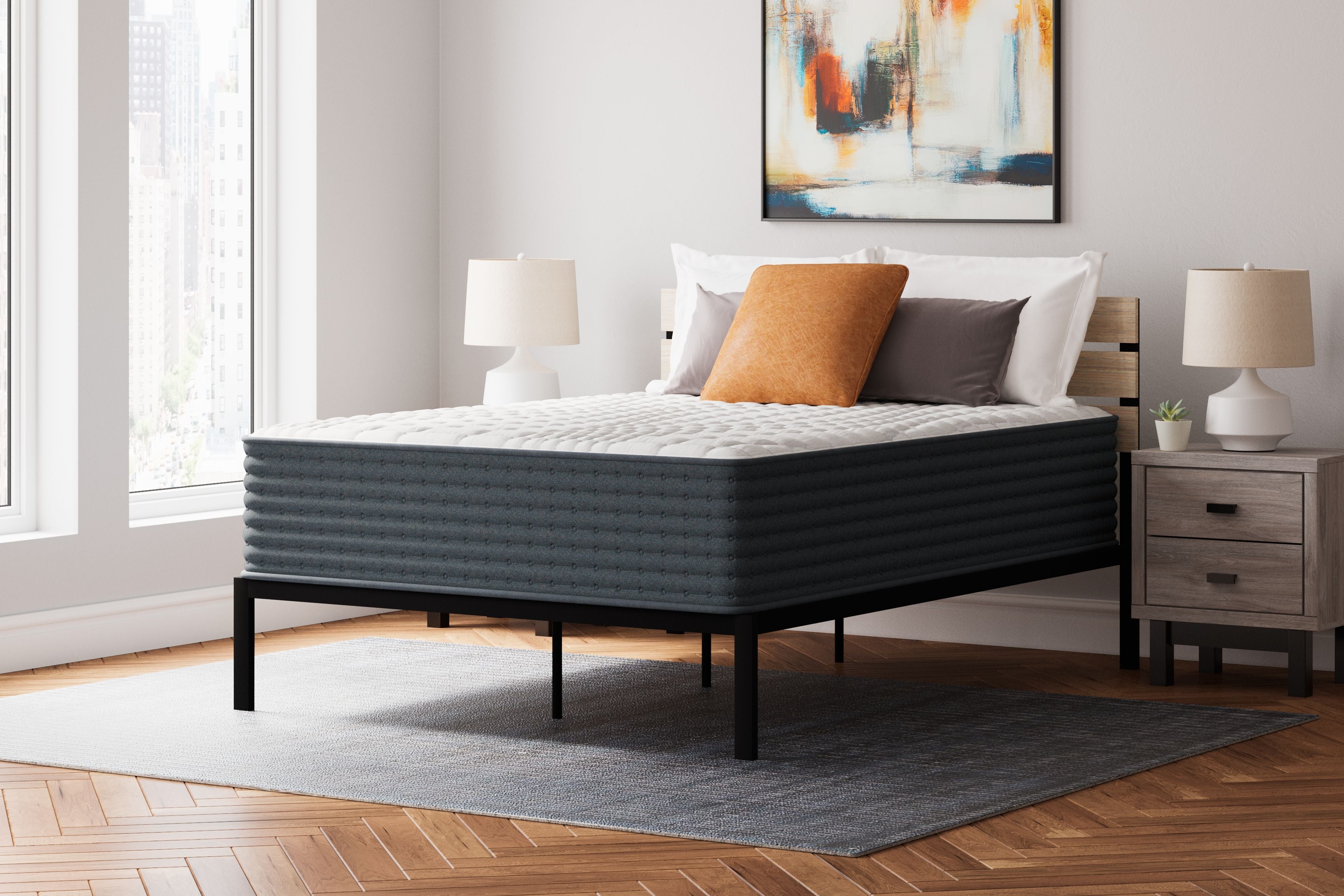 Hybrid mattress with white quilted top and dark gray sides, on a bed frame